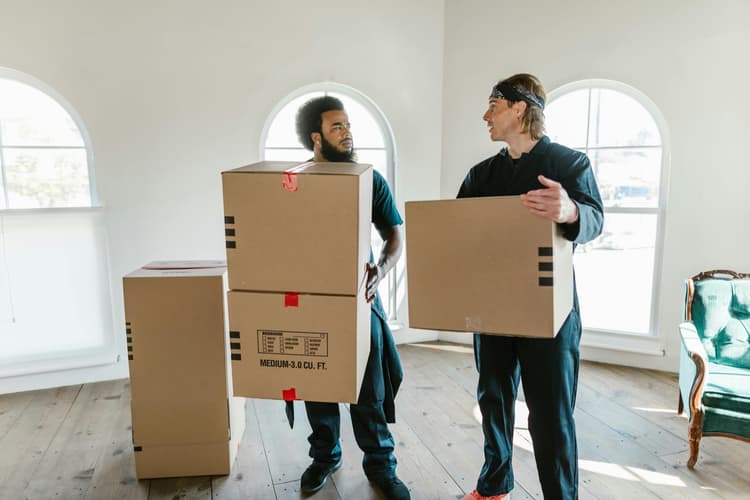 Men carrying boxes inside an apartment