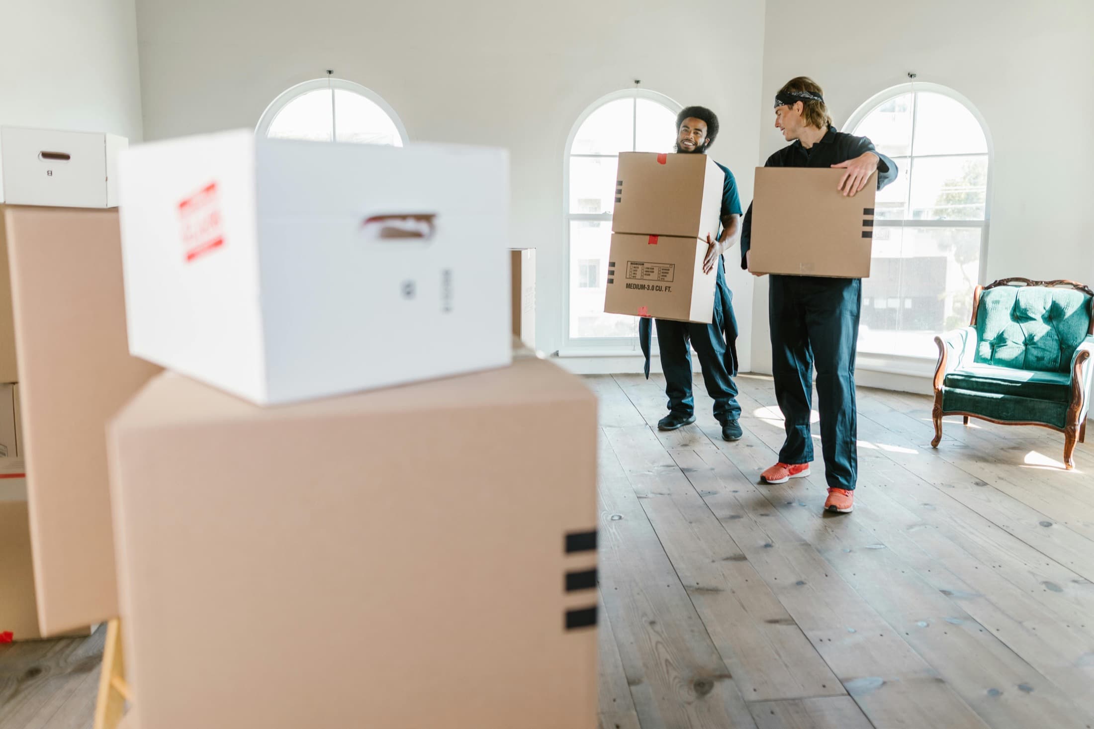 Movers carrying boxes through a bright apartment